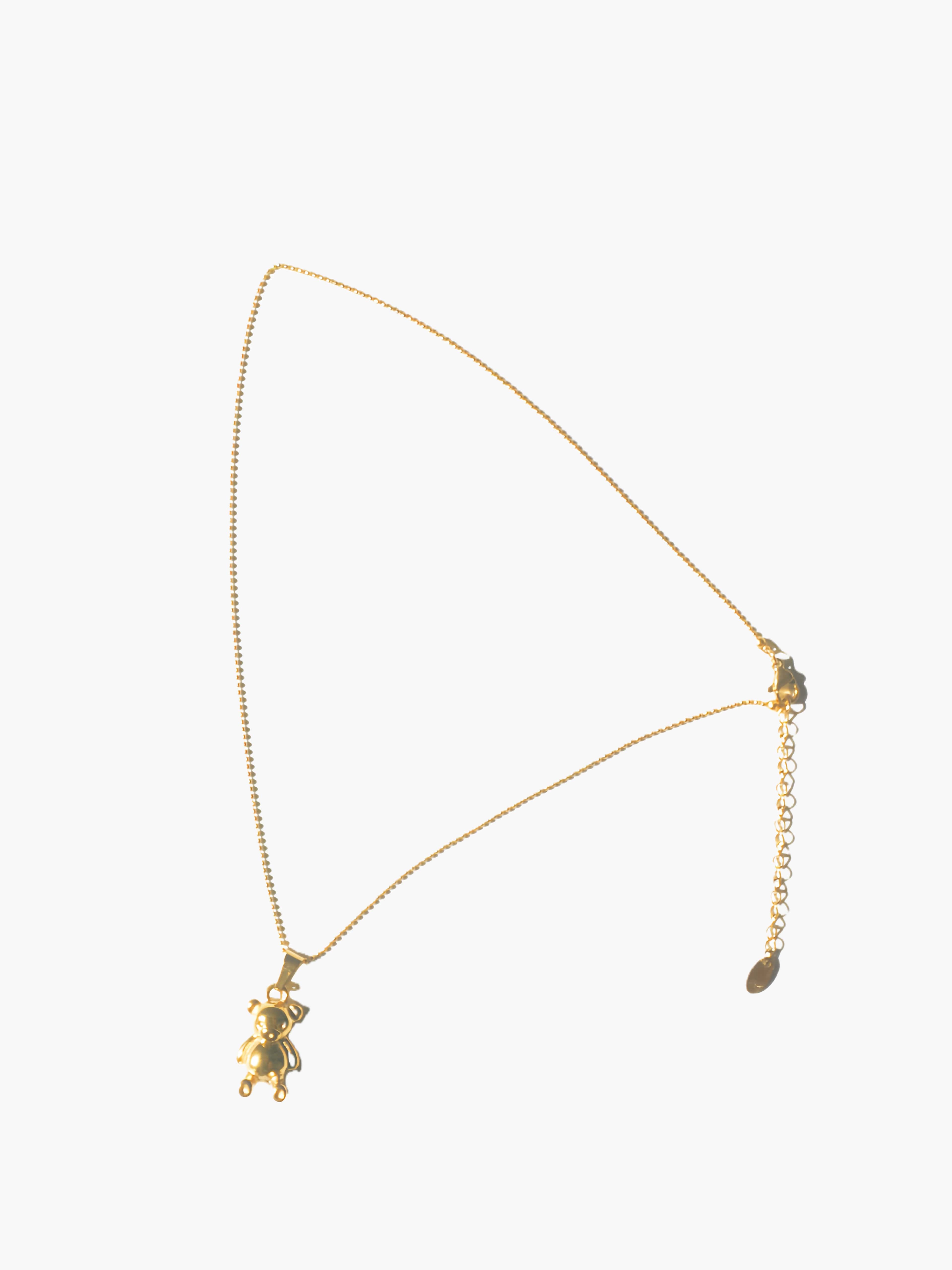 gold necklace with a small teddy bear pendant on a white background