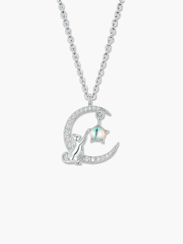 Detailed view of a silver cat moon necklace featuring a feline figure resting on a zircon-studded crescent moon, reaching toward a star-shaped moonstone.