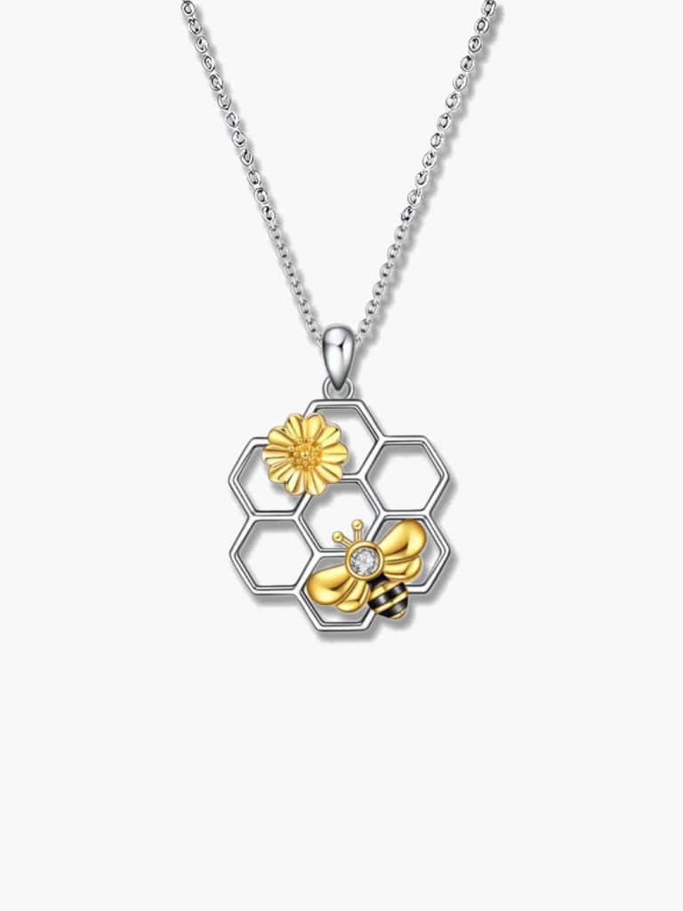An extreme close-up of the detailed silver bee necklace pendant, showing the silver honeycomb and a detailed gold bee and sunflower with a central cubic zirconia.