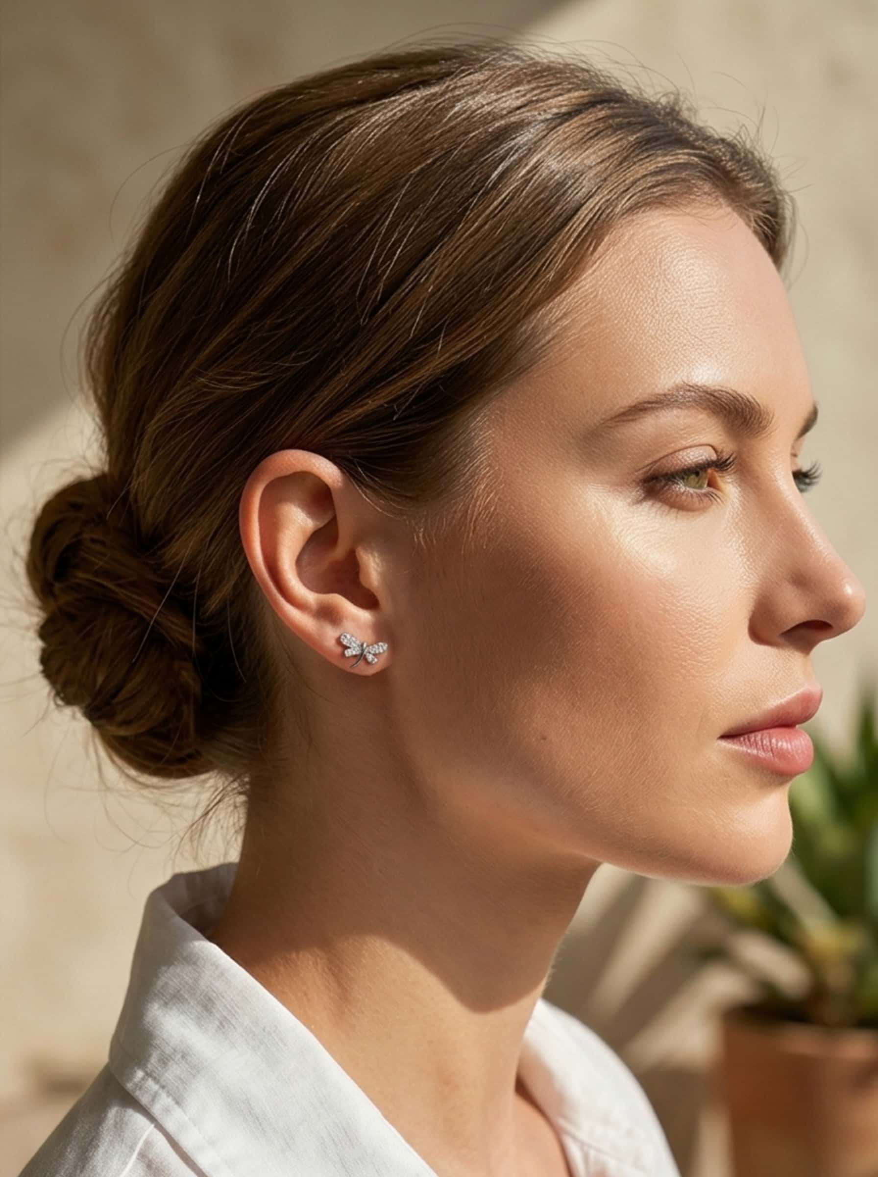Elegant female model in sunlight wearing beautiful silver dragonfly earrings.