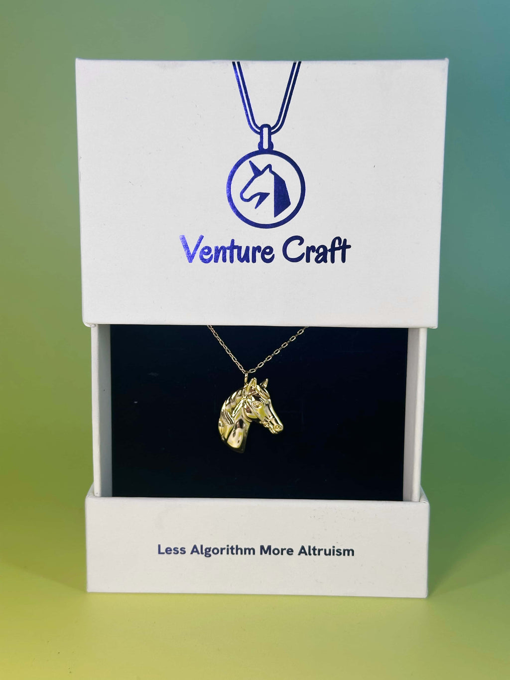 The 18K gold horse necklace presented in its official white Venture Craft gift box featuring the brand logo and slogan 'Less Algorithm More Altruism'