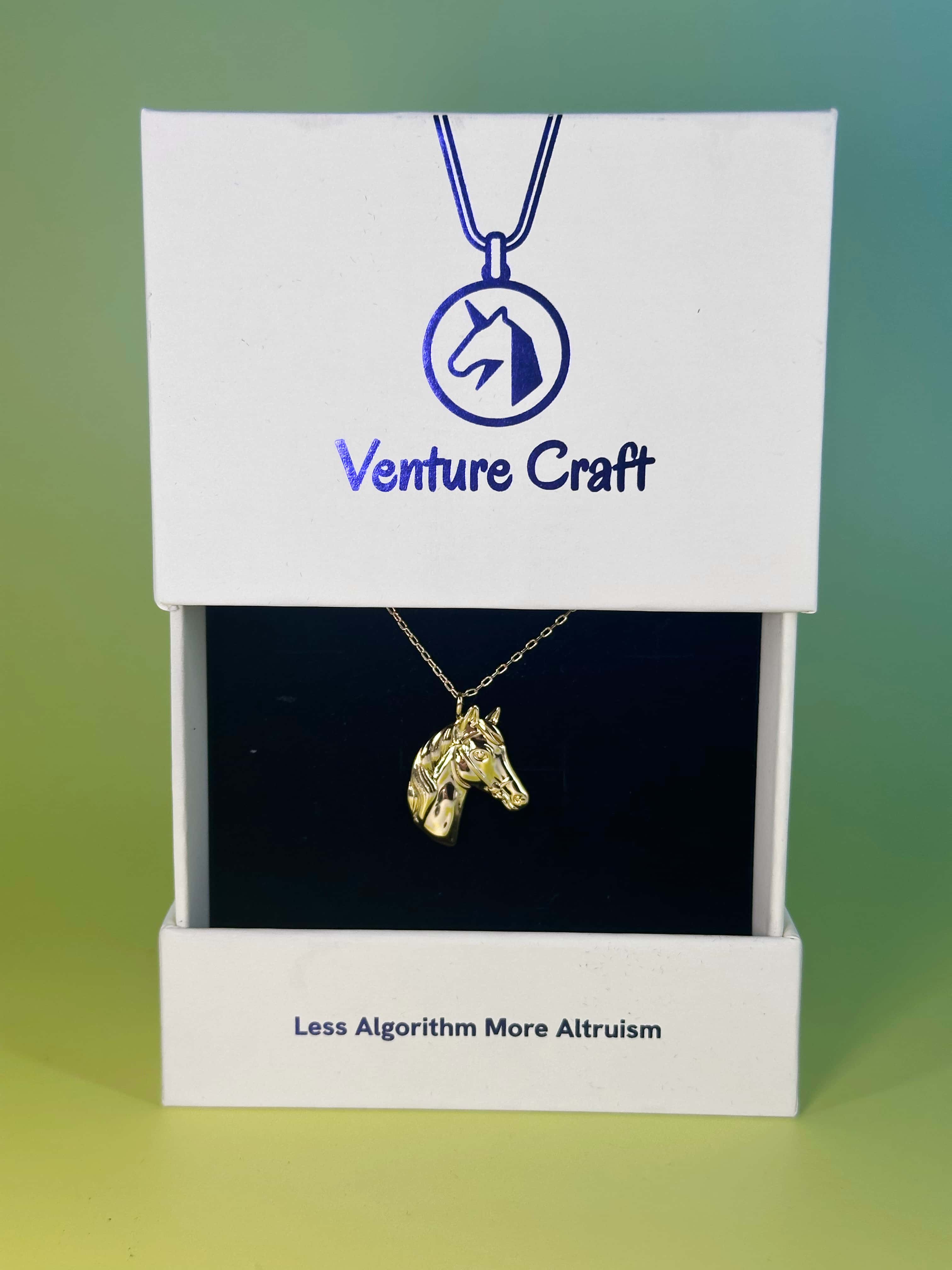 The 18K gold horse necklace presented in its official white Venture Craft gift box featuring the brand logo and slogan 'Less Algorithm More Altruism'