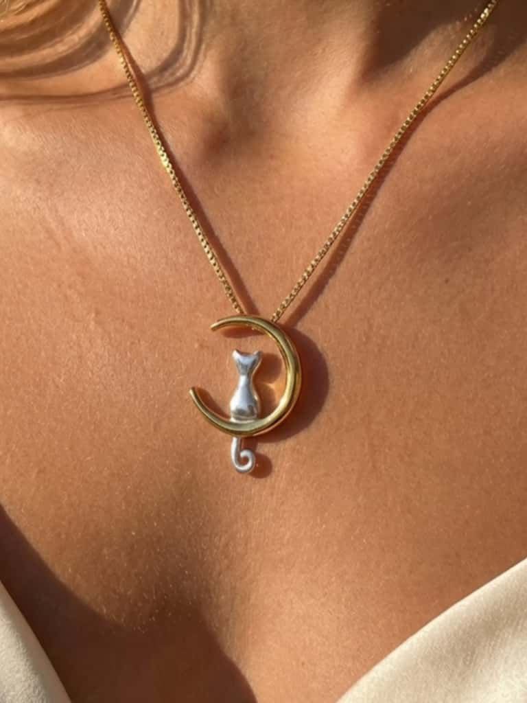 Woman wearing a cat on the moon necklace layered with other jewelry